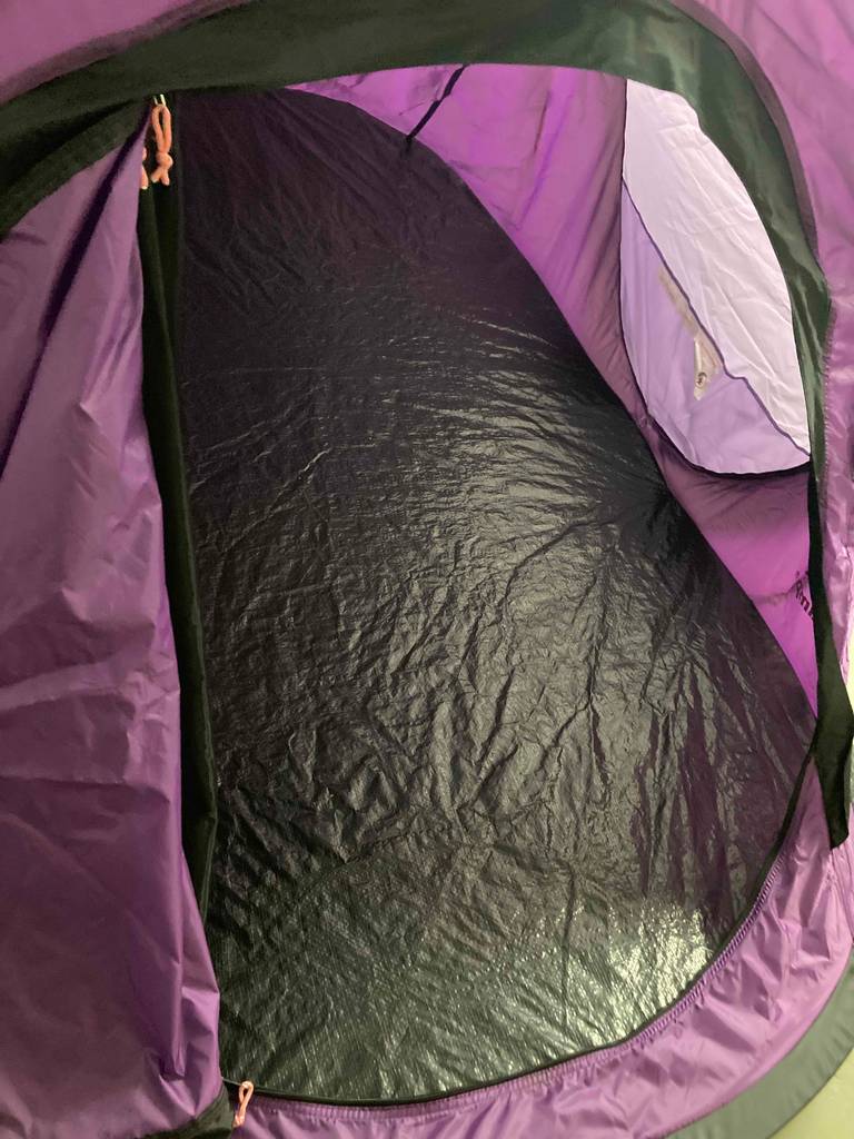 Blick durch den Eingang auf den schwarzen Boden eines violettfarbenen, aufgeschlagenen Einmannzelts im Test.
