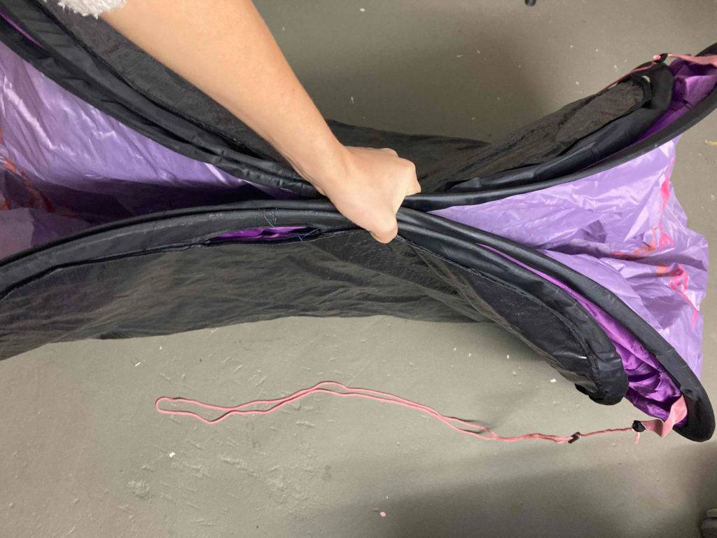 Hand hält ein violettfarbiges und schwarzes Einmannzelt im Test zusammengefaltet.