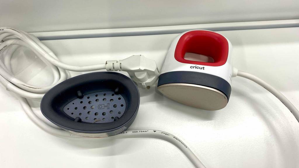 Transferpresse getestet: Eine weiß-rote Mini Thermopresse von Cricut liegt geöffnet auf einem weißen Regal.