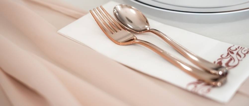 Auf einer Hochzeitstafel mit rosefarbenem Tischtuch und weißem Geschirr liegt das getestete Echtwerk-Besteck in Roségold.