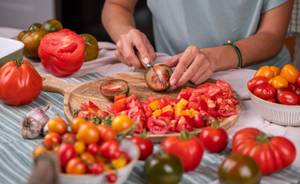 Echtwerk-Messer-Test: Frau schneidet Tomaten auf einem Holzbrett