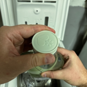 Die Verschlusskappe des Ecover-Waschmittels für schwarze Wäsche wird entfernt.