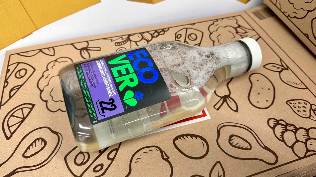 Im Test: Detailansicht einer schäumenden Flasche Waschmittel für schwarze Wäsche, die auf einem Karton liegt.