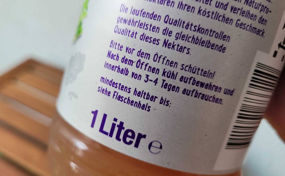 Nahaufnahme des Labels einer Flasche getesteten Rhabarbersaftes mit Mengenangaben und Informationen.