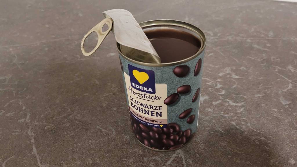 Eine offene Dose mit schwarzen Bohnen im Test steht auf einer grauen Küchenarbeitsplatte.