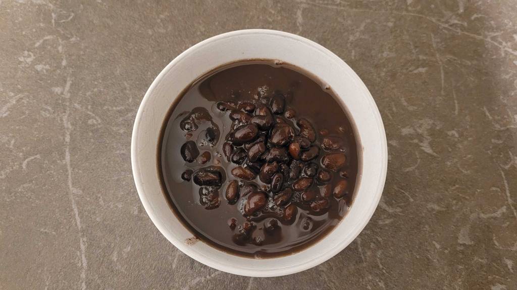 Ansicht von oben auf eine weiße Schüssel mit schwarzen Bohnen im Test.
