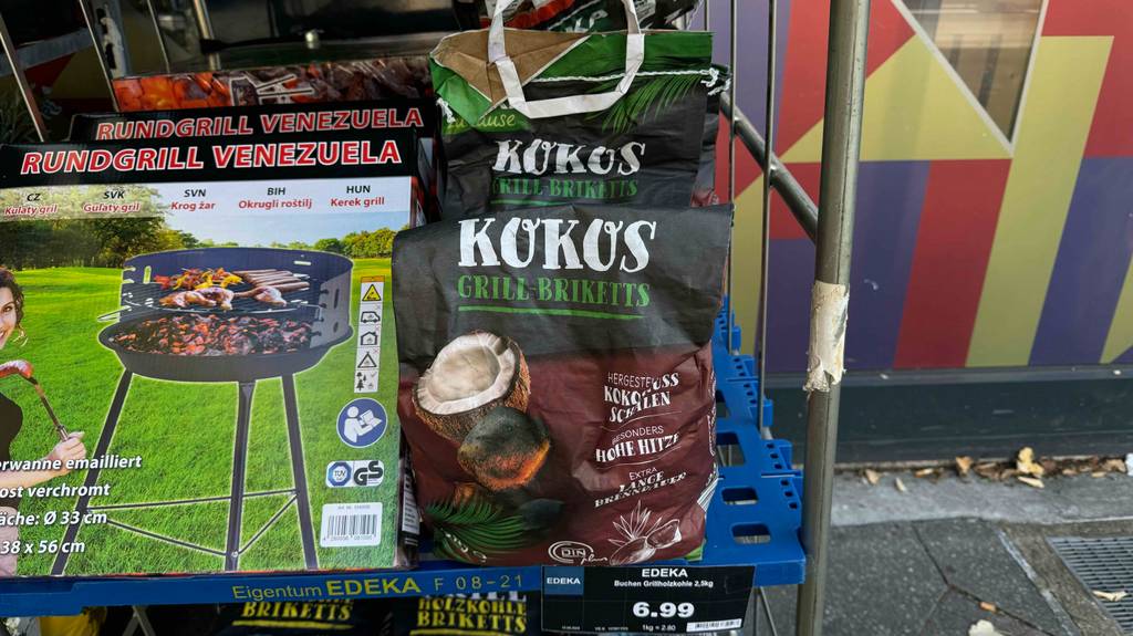 Kokos-Briketts im Test: Eine Packung steht neben einem in Karton verpacktem Rundgrill.