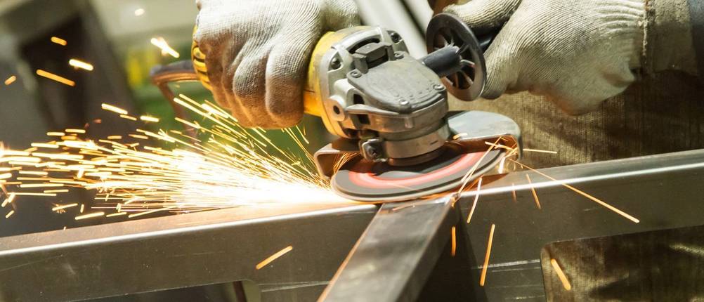 Mit einem DeWalt-Winkelschleifer wird ein kleiner Stahlträger abgeschliffen.