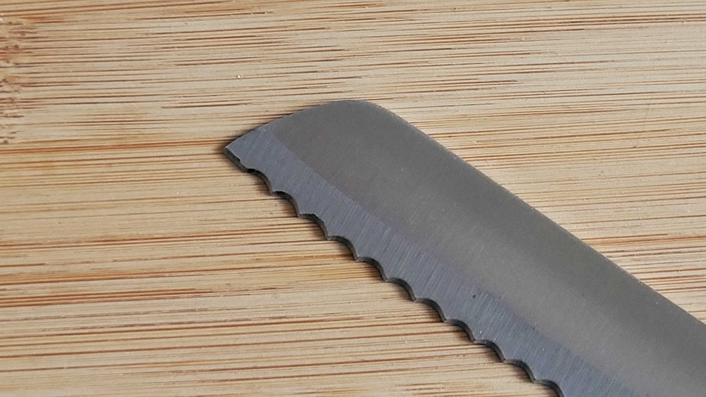Brotmesser im Test: Nahaufnahme der Schneide eines Brotmessers im Test auf einer Holzfläche.