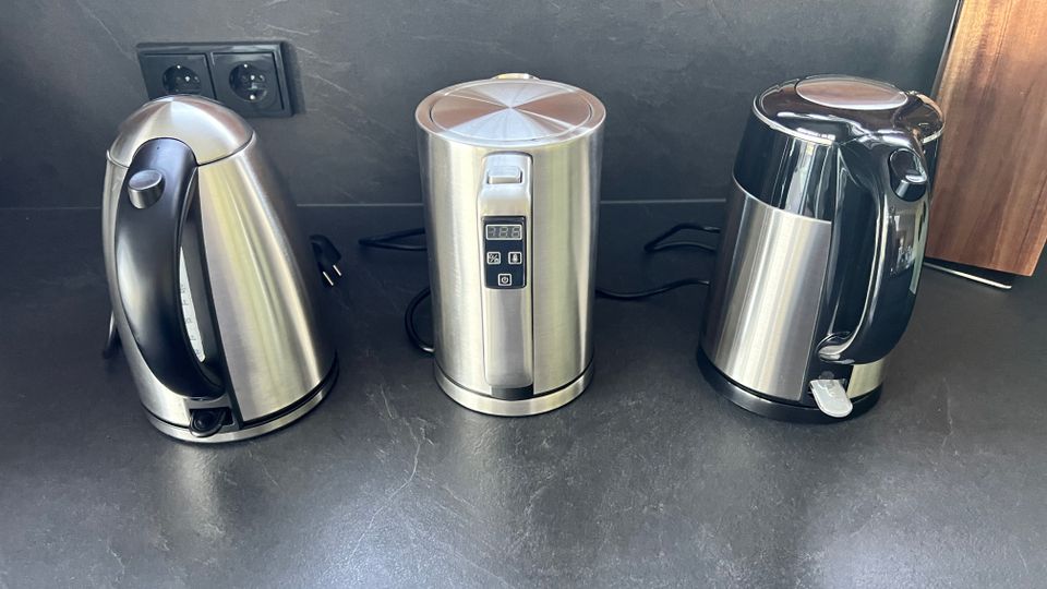 Drei Edelstahl-Wasserkocher auf der Küchen-Arbeitsplatte nebeneinander stehend