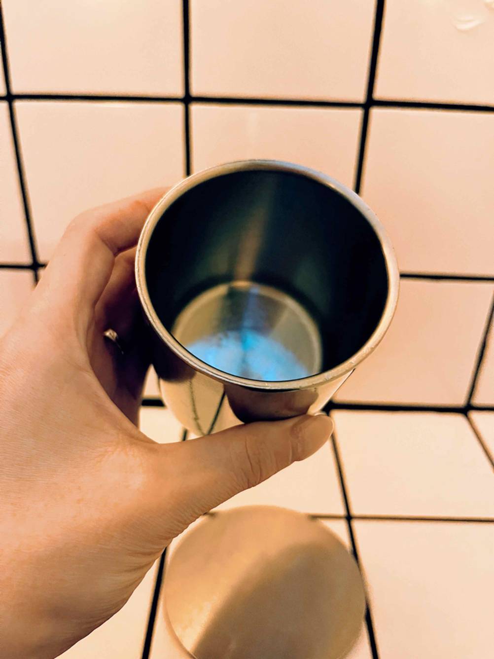 Eine Hand hält einen getesteten Edelstahlbecher.