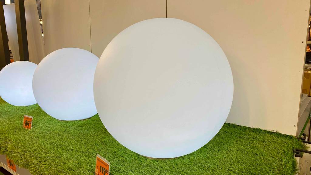 Leuchtkugel Garten im Test: mehrere Leuchtkugeln leuchten nebeneinander auf einem Kunstrasen.
