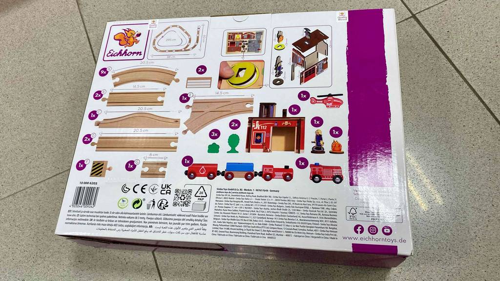 Rückwärtige Ansicht einer eingepackten Holzeisenbahn im Test: Es sind die in der Verpackung enthaltenen Bauteile zu erkennen.