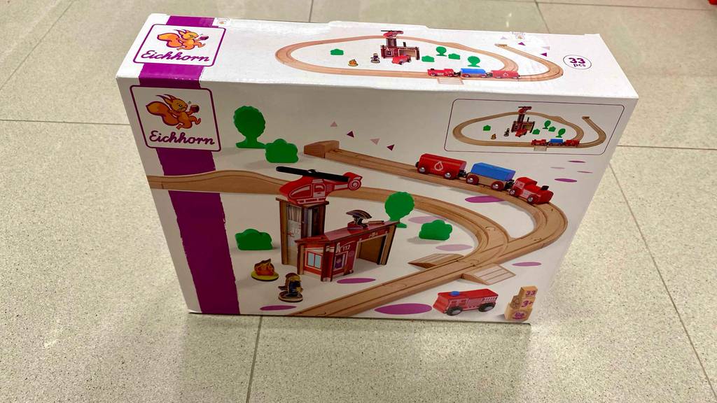 Holzeisenbahn getestet: Eine bunte Verpackung mit einer Eichhorn-Holzeisenbahn steht auf einem hellen Fliesenboden.
