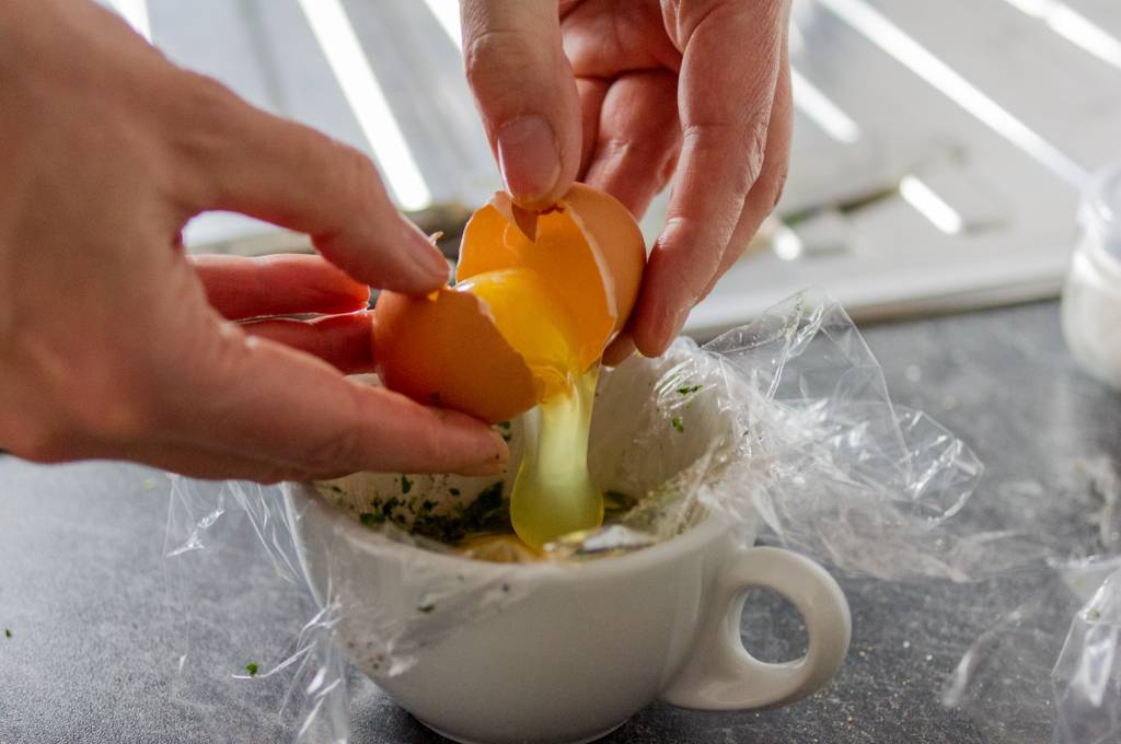 Eier-Pochierer-Test: Ein Ei wird in eine kleine Tasse zum Pochieren aufgeschlagen. 