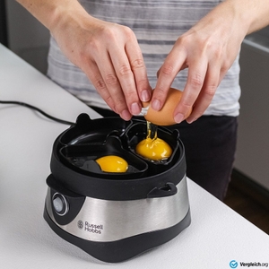 Eierkocher-Test: Eine Person schlägt rohe Eier in die Pochier-Schalen eines Eierkochers.