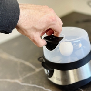 Eine Person greift die Abdeckung des getesteten Eierkochers von Russell Hobbs.