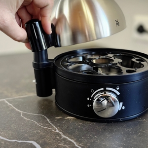 Eine Person setzt die Abdeckhaube auf den getesteten Eierkocher von WMF.