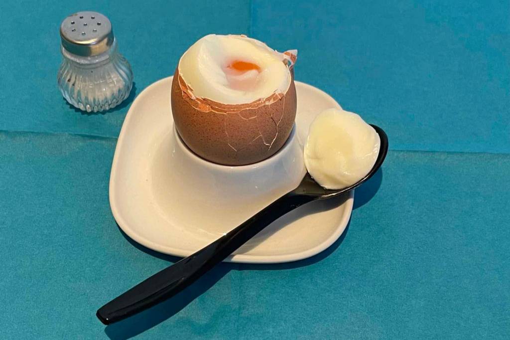 Im Test: Eierlöffel mit Stück Ei liegt auf Eierbecher mit gekapptem Ei, im Hintergrund ein Salzstreuer.