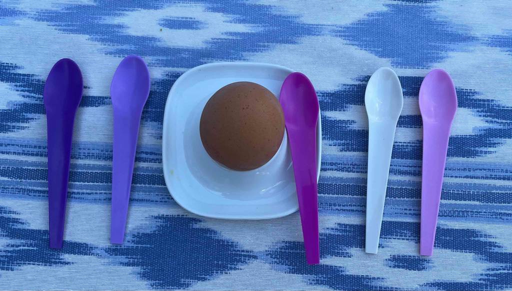 Im Test: Ei Ei im Eierbecher steht zwischen mehreren verschiedenfarbigen aufgereihten Eierlöffel.