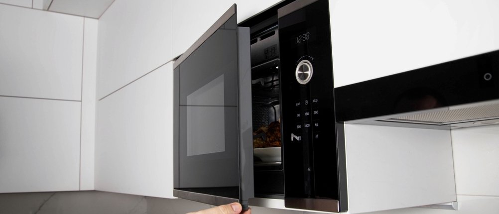 Einbau-Mikrowellen-Test: Eine in einer weißen Küche eingebaute Mikrowelle wird geöffnet.