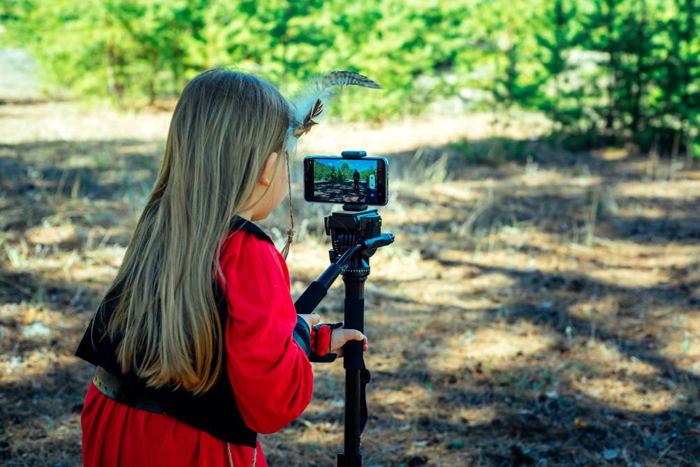 Einbeinstativ im Test: Ein Mädchen mit Feder im Haar nutzt ein Einbeinstativ mit Handy.