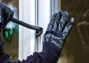 Hausratversicherungs-Test: Ein Einbrecher versucht ein Fenster aufzuhebeln.
