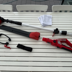 Die Einzelteile der Einhell-Akku-Teleskop-Heckenschere GE-HH liegen neben der Anleitung auf einem Tisch