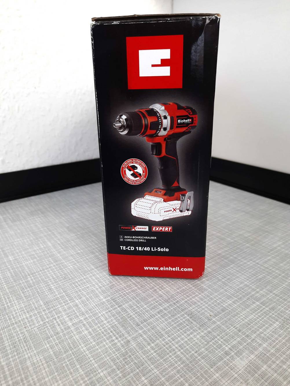 Die Seite einer Originalverpackung des getesteten Einhell-Akkuschrauber 18V auf einer grauen Fläche.
