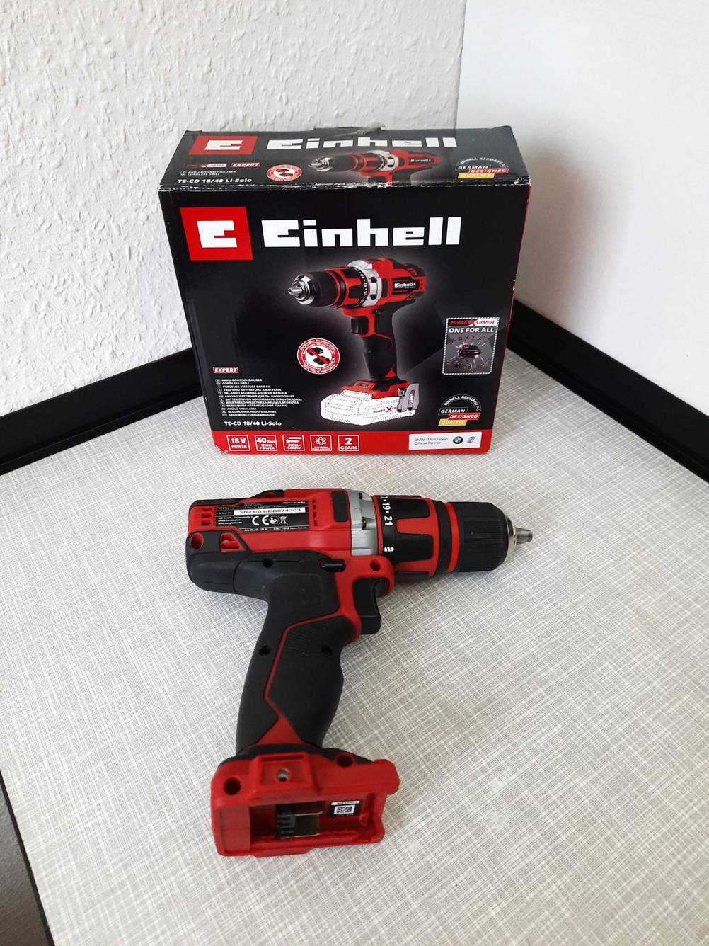 Einhell-Akkuschrauber 18V-Test: Ein Akkuschrauber liegt vor seiner Originalverpackung auf einer grauen Fläche.