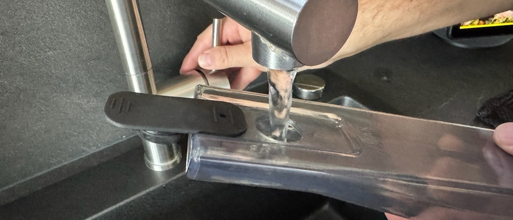 Eine Hand füllt Wasser in den Wasserbehälter des Einhell CLEANEXXO