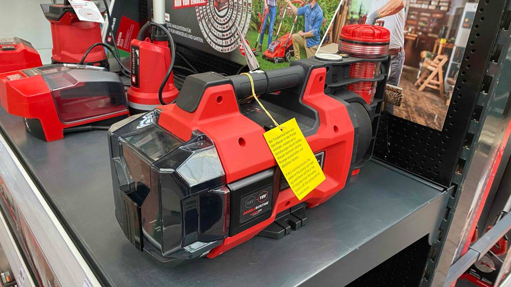 Einhell-Gartenpumpe getestet: Eine rote Einhell-Gartenpumpe steht neben anderen Gartenprodukten auf einem Verkaufsregal.