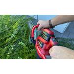 Zwei Hände halten die Einhell GE-EH 7067 während der Verwendung an zwei Griffen fest