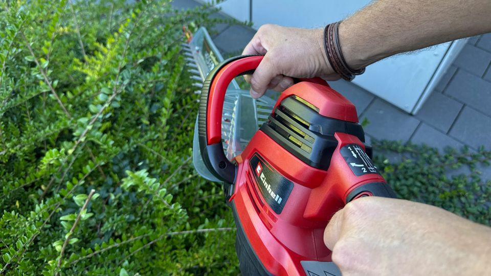 Zwei Hände halten die Einhell GE-EH 7067 während der Verwendung an zwei Griffen fest