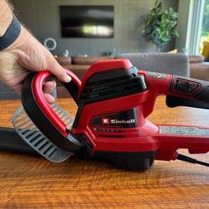 Eine Hand hält die Einhell GE-EH 7067 am vorderen Griff fest.