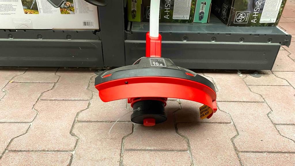 Einhell-Rasentrimmer im Test: Detailansicht der Trimmereinheit, auf der Infos zur Lautstärke stehen.