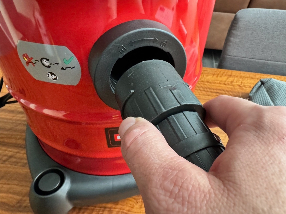 Eine Hand befestigt den Schlauch des Einhell TC-AV 1720 DW