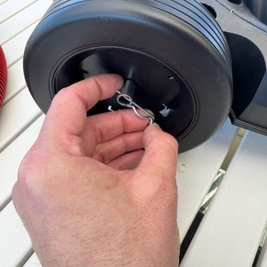 Eine Hand befestigt eine Sicherung an einem Reifen des Einhell TE-VC 2025 SACL