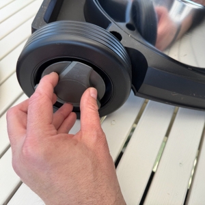 Eine Hand befestigt die Abdeckung der Reifen des Einhell TE-VC 2025 SACL