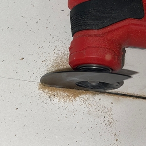 Im Fokus steht das kreisförmige Sägeblatt des Einhell Varrito, das sich in eine weiße Holzfläche schneidet. Holzspäne liegen um den Schnitt.