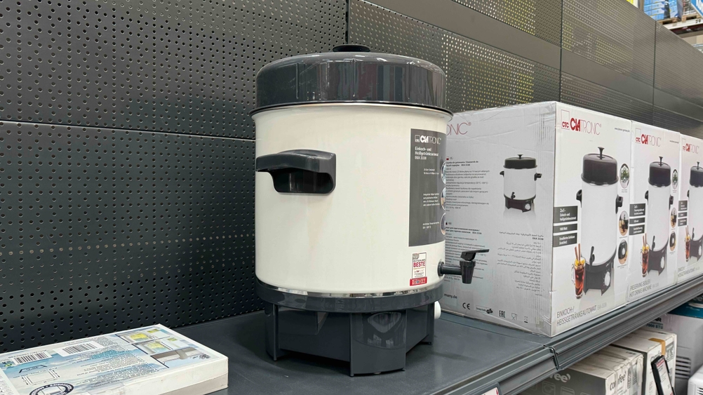 Einkochautomat getestet: Ein Gerät von der Seite im Regal stehend, im Hintergrund originalverpackte Einkochautomaten.