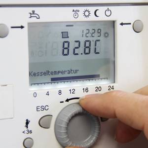 Eine Hand justiert den Brennwertkessel über dessen Steuerungselement.