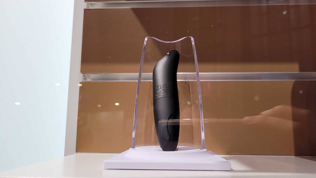 Ein schwarzer Squirting-Dildo im Test steht ausgestellt auf einem weißen Podest im Regal.