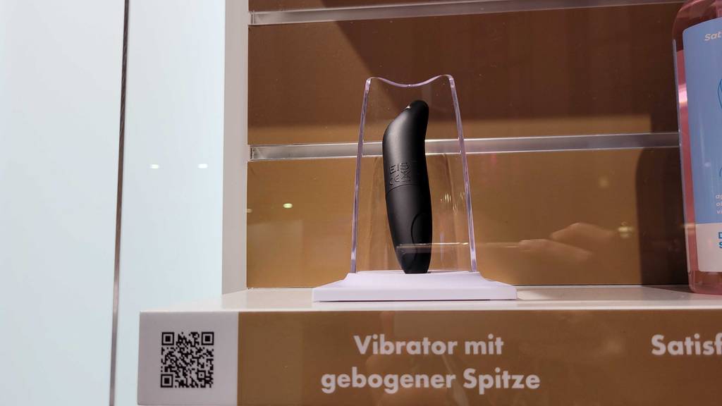 Squirting-Dildo-Test: Schwarzer Dildo der Marke Eis mit gebogener Spitze steht in einem Ausstellungsbereich.