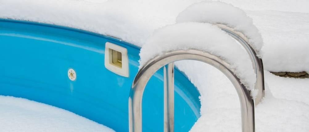 Eisdruckpolster getestet: Eine verschneite Poolleiter eines Rundpools in Nahaufnahme.