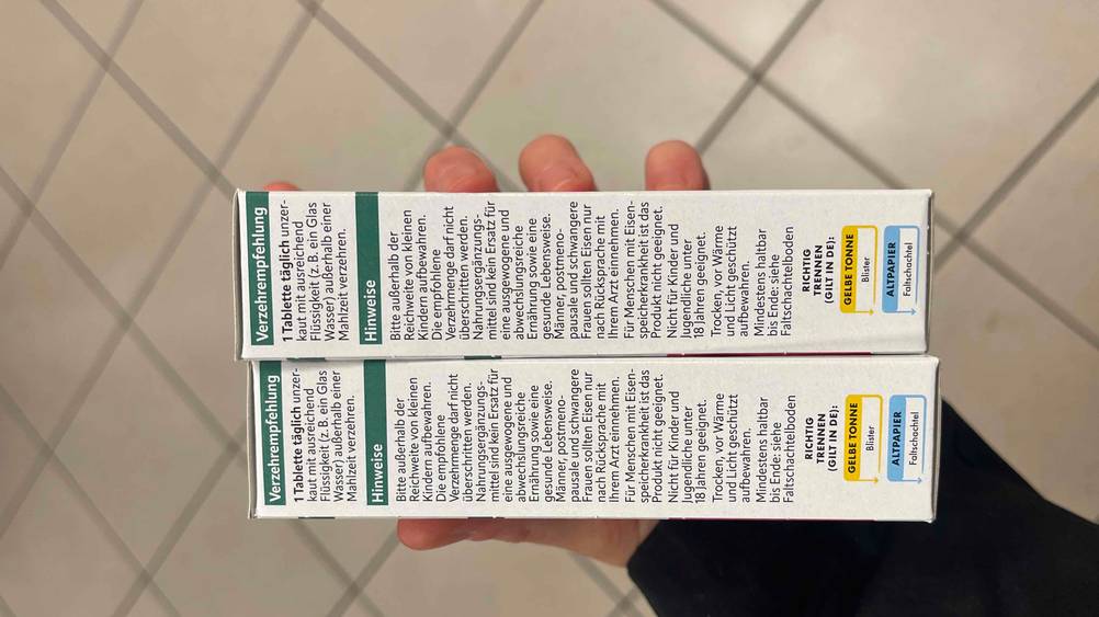 Eisentabletten getestet: Eine Hand hält zwei Packungen mit der Seite mit Anwendungshinweisen nach oben.