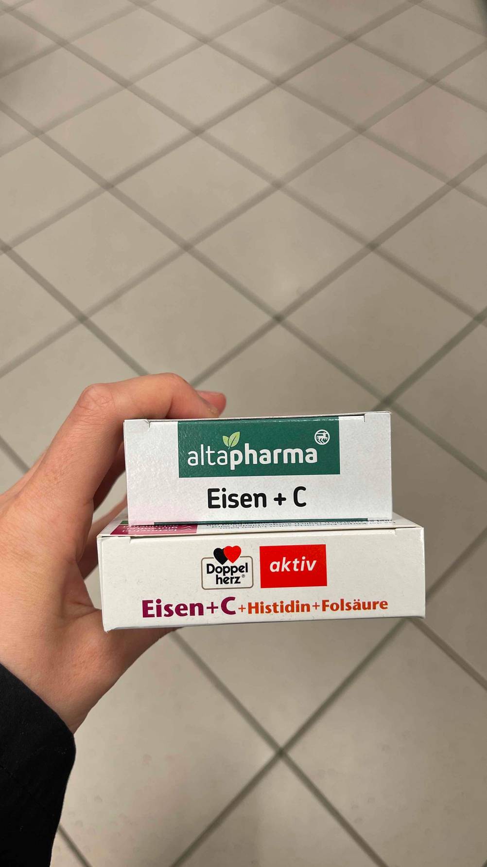 Eisentabletten-Test: Eine Hand hält zwei Packungen unterschiedlicher Sorten.