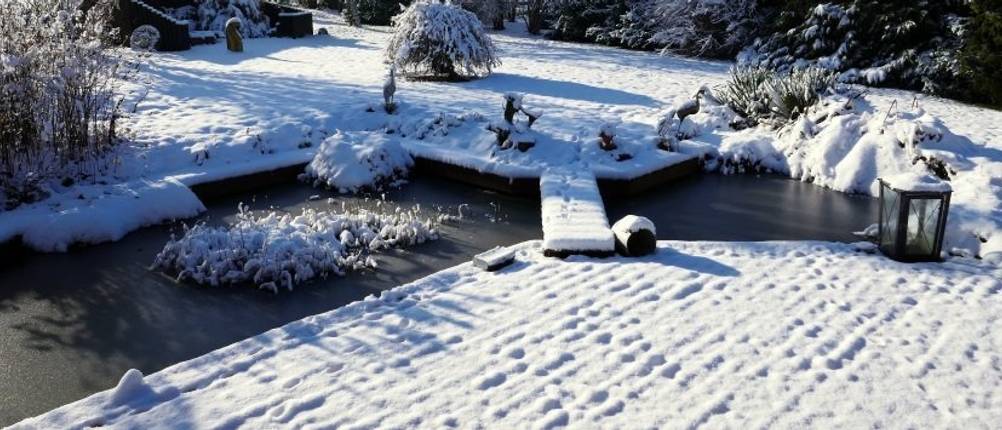 Eisfreihalter-Test: Eine verschneite Terrasse und Garten und ein kleiner Teich.