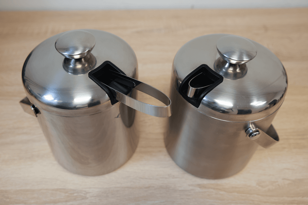 Eiskübel im Test: Auf einem Tisch stehen zwei Edelstahl-Eiskübel mit einem Fach für eine Eiszange im Deckel.