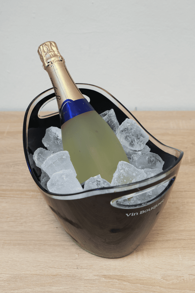 Eiskübel-Test: Ein Eiskübel steht auf dem Tisch und ist mit Eiswürfeln und einer Flasche Sekt gefüllt.